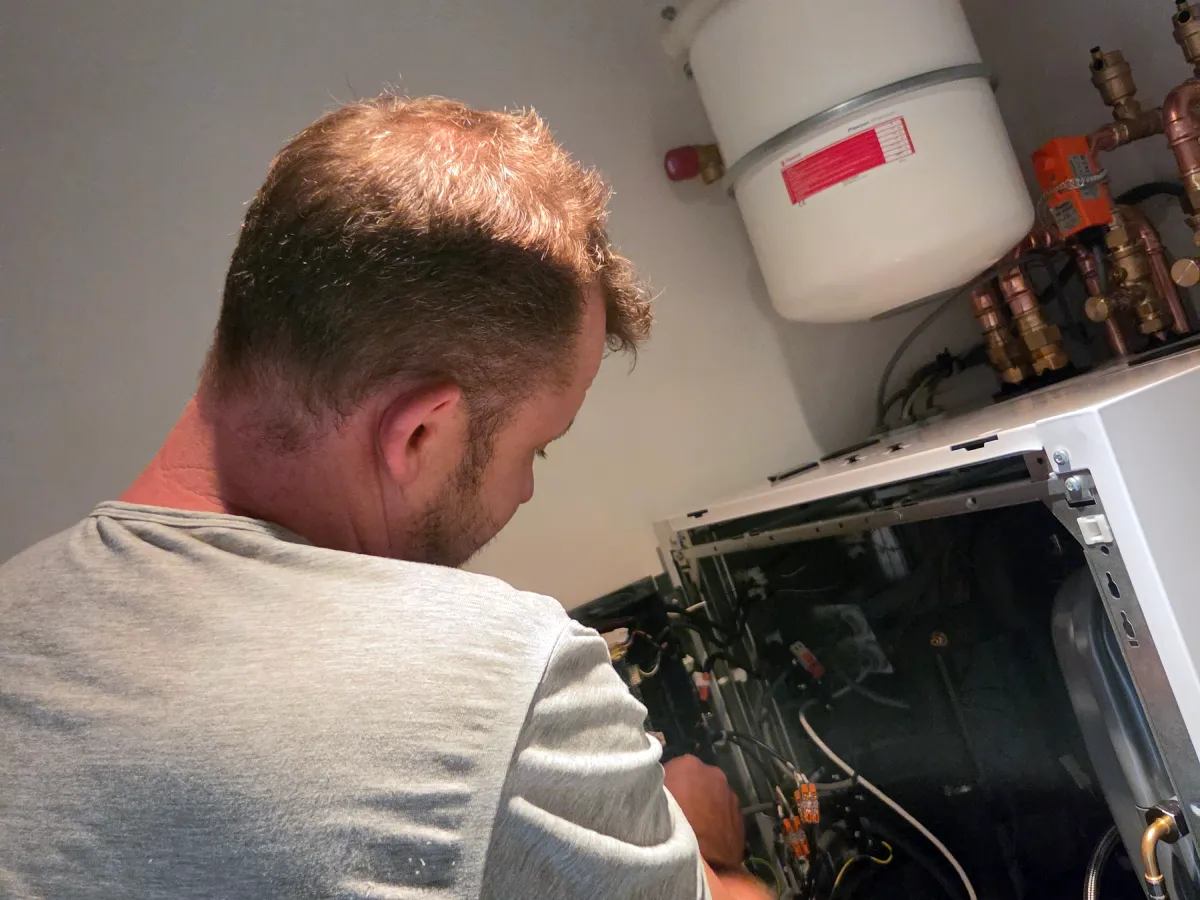 Monteur van Installatiebedrijf Jonker aan het werk aan een open cv-ketel in Koewacht